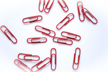 Closeup of red paper clips on a white background lie abstract.