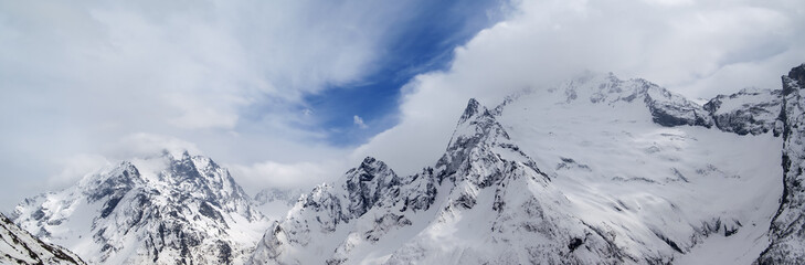 Fototapeta na wymiar Panorama of gray high mountain peaks covered with ice