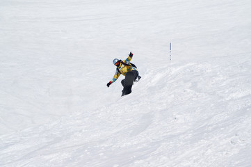 Fototapeta na wymiar Snowboarder jumping on snowy ski slope at high winter mountains