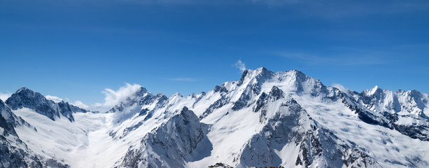 Fototapeta na wymiar Panorama of snow-capped mountain peaks and beautiful blue sky