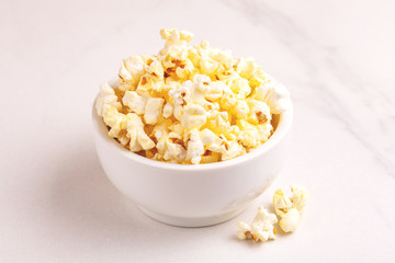 Tasty salty popcorn in bowl on light marble backgraund