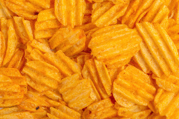 Crispy corrugated potato chips background. Junk food