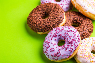 Assorted delicious donuts on bright green background