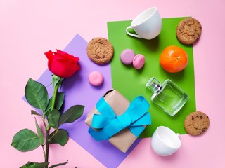 Flat lay Valentine's Day photo. Red rose, macarons cookies, citrus, gift box, two cup and perfume. Present and surprise