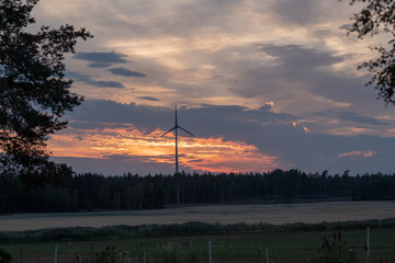 sunset over a field with wind turbine