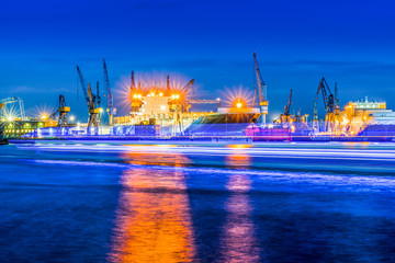 Obraz premium Container ships, docks and cranes in the harbor at night, Hamburg, Germany.