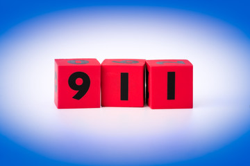Red cubes spelling 911 isolated on white and blue background.