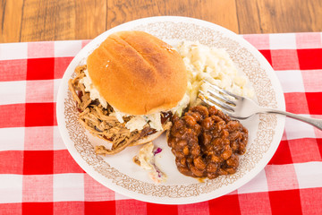 Coleslaw on Pulled Pork BBQ Sandwich with Baked Beans and Potato Salad