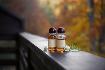 Bottles with essential oil and flowers on blurred background. Space for text