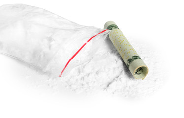 Cocaine in plastic bag and rolled money bill on white background