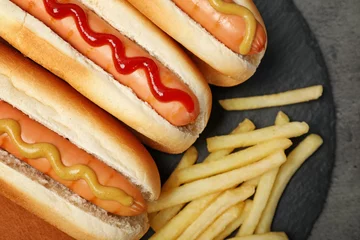 Tuinposter Delicious hot dogs and french fries on slate plate, top view © New Africa
