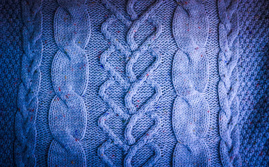 Beautiful texture of a soft warm natural sweater with a knitted pattern of threads. The background