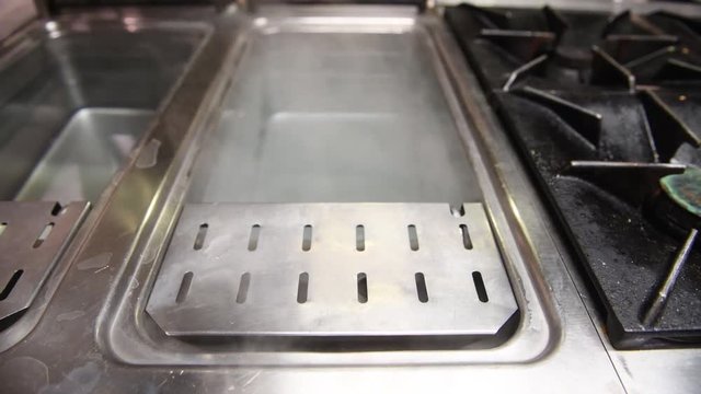 Fryer cleaning with hot boiling water in big restaurant kitchen, bottom up panning