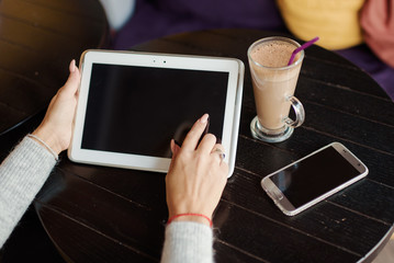 Girl hands with digital tablet and cup of coffee on a wooden table