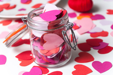 closeup of paper heart falling from glass container on white background - valentine's day concept