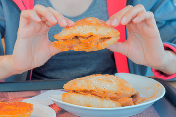 Woman holding meat sandwiches in hands and going to eat.