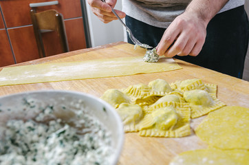 Chef putting cheese and spinach filling on a pasta dough making homemade ravioli