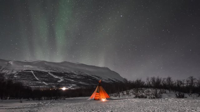 Northern lights over tent and mountain in Lapland