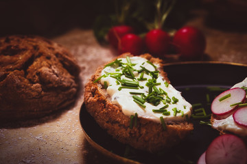 Selbstgebackenes Brot mit Kräuterquark serviert auf dem Backblech