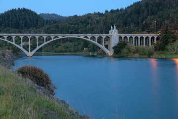 Obraz premium The Rogue River bridge with the obelisk illuminated at sunset in Gold Beach, Oregon, USA