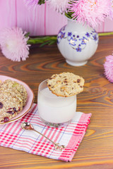 Obraz na płótnie Canvas Homemade cookies: coconut, oatmeal, chocolate, on a wooden table, with a glass of milk, against the background of a summer composition with flowers