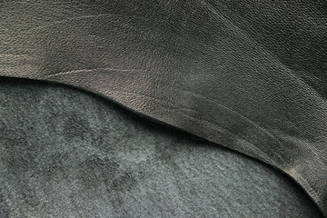 A piece of black suede and leather. Material of animal origin. Skin texture. Background. Close-up.