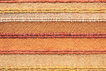 The texture of the striped orange fabric with a large interweaving of threads and fibers. Close-up. Background.