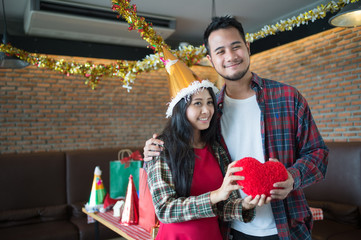 man and woman holding red heart pillow on hand in the party, concept of love and celebrate