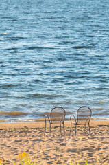 Two empty chairs on the shore