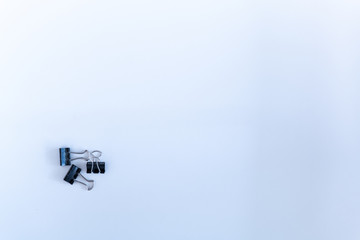 Three fold back paper clips at lower left corner on white background