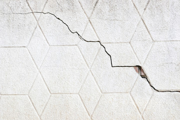 Obraz premium The texture of the surface of the old gray wall with a crack. Grunge background and wallpaper with space for text or image. Empty template and mockup for designers.