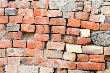 Dilapidated wall of old red bricks and stones. The texture of the brickwork. Grunge background. Template and mockup for designers.