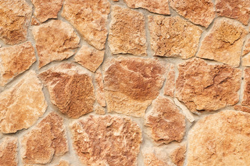 Decorative beige facing stone on the wall. The texture of the wall of the old stone. Background and wallpaper. Close-up.