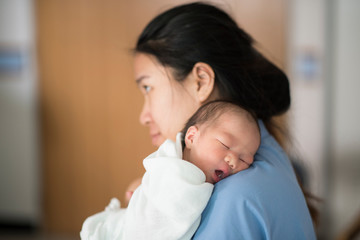 Young Mother holding a newborn baby in her arms in hospital