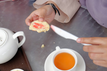 Young muslim woman sweep the strawberry jam on scone at the strawberry farm at Cameron Highland.
