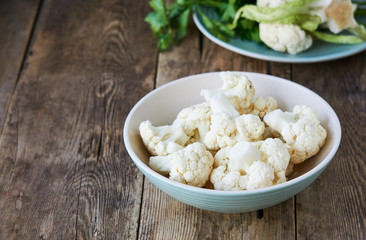 Pieces of raw cauliflower in a bowl on a wooden table