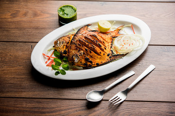 Tandoori Pomfret fish cooked in a clay oven and garnished with lemon , mint, cabbage and carrot...