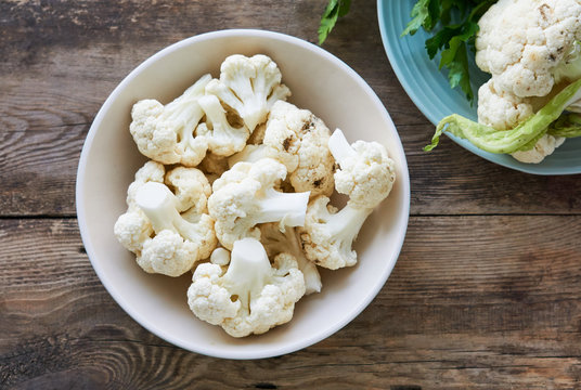 Pieces of raw cauliflower in a bowl on a wooden table