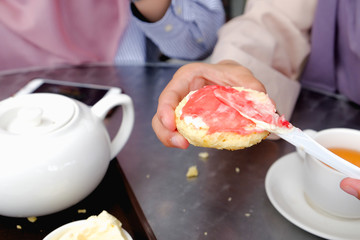 Young muslim woman sweep the strawberry jam on scone at the strawberry farm at Cameron Highland.