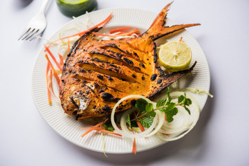 Tandoori Pomfret fish cooked in a clay oven and garnished with lemon , mint, cabbage and carrot...