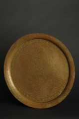 ancient oriental metal tray on dark background. antique bronze tableware