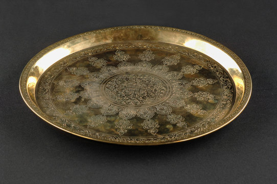 ancient oriental metal tray on dark background. antique bronze tableware