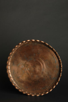 ancient oriental metal tray on dark background. antique bronze tableware