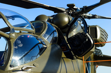 Military helicopter with open door and bulletproof cockpit, detail, air force, aviation and aerospace industry, blue sky on background 