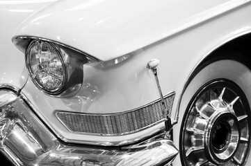 Headlight, chrome bumper and tire of retro car with white bodywork, detail of classic vehicle,...