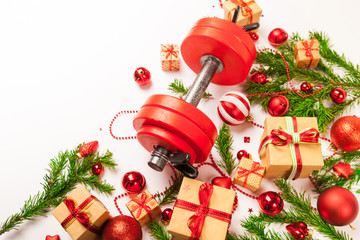 Christmas or New Year on a white background. Composition with dumbbells, gift, red and gold glass balls, fir tree branches for healthy lifestyle and sport