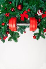 Christmas or New Year on a white background. Composition with dumbbells, gift, red and gold glass balls, fir tree branches for healthy lifestyle and sport