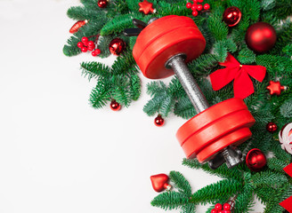 Christmas or New Year on a white background. Composition with dumbbells, gift, red and gold glass balls, fir tree branches for healthy lifestyle and sport