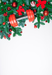Christmas or New Year on a white background. Composition with dumbbells, gift, red and gold glass balls, fir tree branches for healthy lifestyle and sport