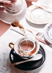 Papier Peint photo Lavable Theé Hot Apple Tea served by pouring from mug through stainless steel tea strainer infuser in porcelain vintage cup.